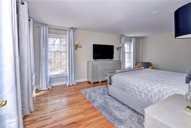 bedroom featuring baseboards, multiple windows, and wood finished floors