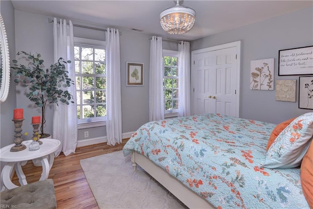 bedroom featuring multiple windows, wood finished floors, visible vents, and baseboards