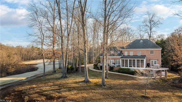 rear view of house featuring a lawn and a sunroom