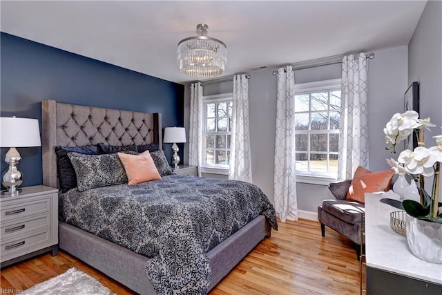 bedroom with a chandelier, baseboards, and light wood-style flooring