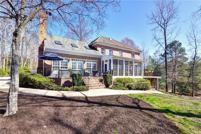 back of house featuring brick siding and a sunroom