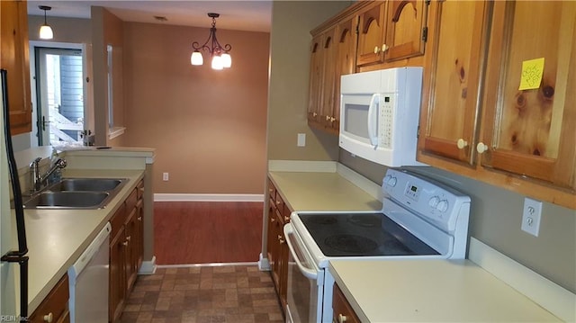 kitchen featuring white appliances, light countertops, brown cabinets, and a sink