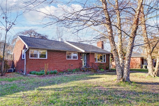 view of front facade featuring a front yard, brick siding, roof with shingles, and a chimney