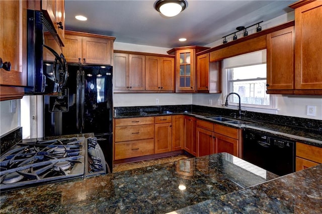 kitchen featuring brown cabinetry, stovetop, a sink, glass insert cabinets, and dishwasher