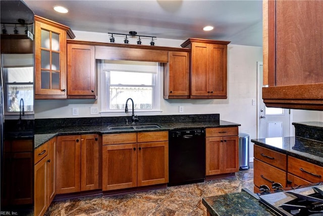 kitchen featuring dark stone counters, black dishwasher, brown cabinetry, and a sink