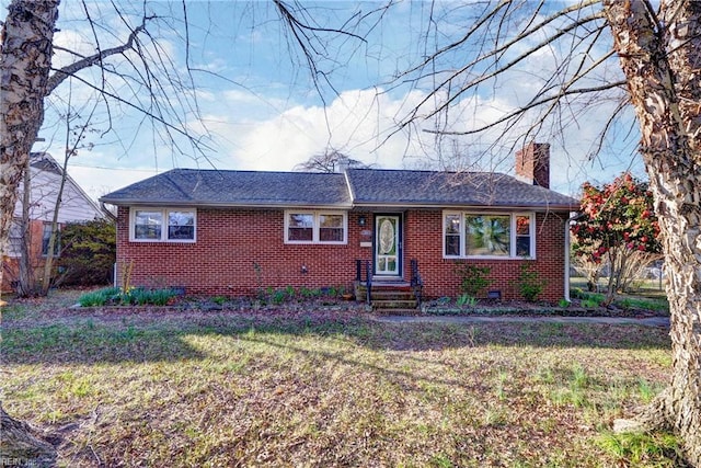 ranch-style house featuring brick siding, a chimney, a front lawn, and a shingled roof