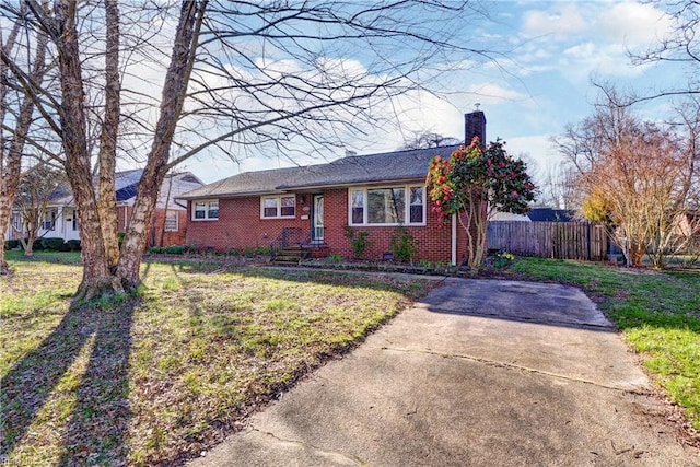 view of front of home featuring a front yard, fence, brick siding, and a chimney