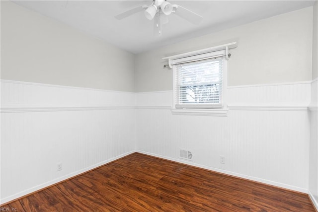 unfurnished room featuring visible vents, a wainscoted wall, wood finished floors, and a ceiling fan