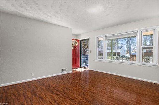 spare room with visible vents, baseboards, and wood finished floors