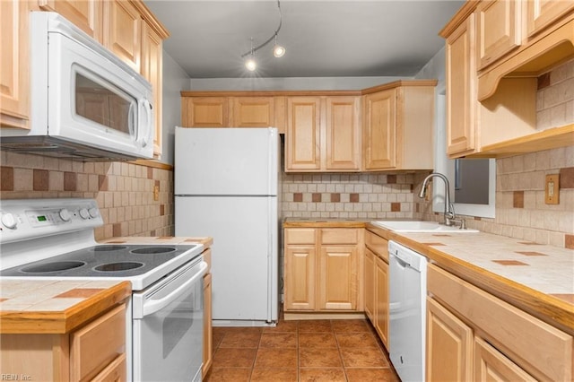 kitchen with light brown cabinetry, a sink, tasteful backsplash, white appliances, and tile counters