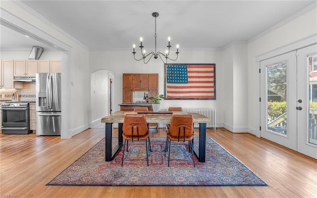 dining area with arched walkways, a notable chandelier, light wood-style flooring, and crown molding