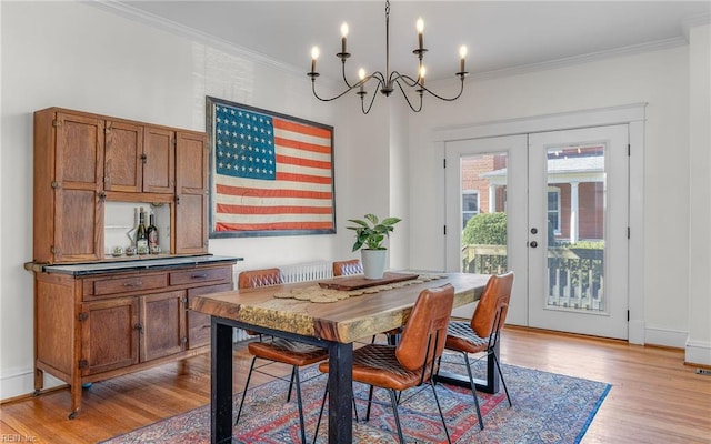 dining area featuring a chandelier, light wood-style flooring, french doors, and crown molding