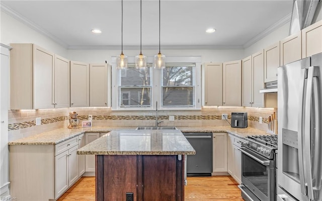 kitchen with a kitchen island, crown molding, under cabinet range hood, appliances with stainless steel finishes, and a sink