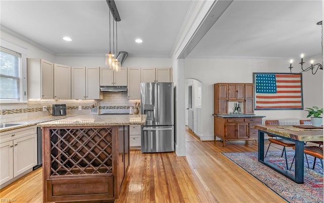 kitchen with under cabinet range hood, decorative backsplash, ornamental molding, and stainless steel fridge with ice dispenser