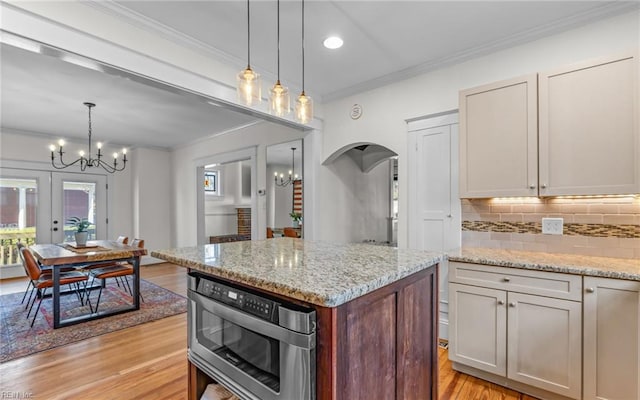 kitchen with arched walkways, a chandelier, crown molding, and light wood finished floors