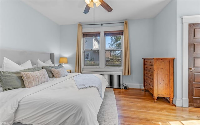 bedroom with light wood-type flooring, baseboards, a ceiling fan, and radiator heating unit