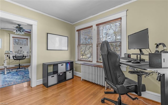 office space featuring crown molding, light wood-style flooring, a ceiling fan, and baseboards