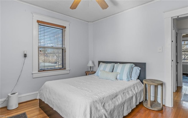 bedroom featuring multiple windows, crown molding, and wood finished floors