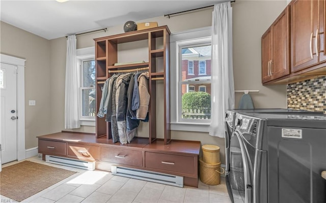 clothes washing area featuring baseboards, washing machine and dryer, baseboard heating, light tile patterned flooring, and cabinet space