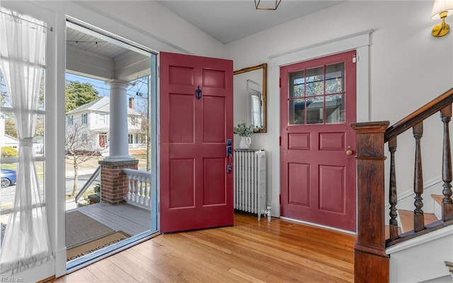 entrance foyer with stairs, decorative columns, wood finished floors, and radiator heating unit