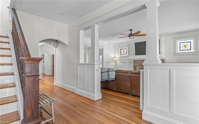 hallway featuring stairs, decorative columns, wood finished floors, and arched walkways