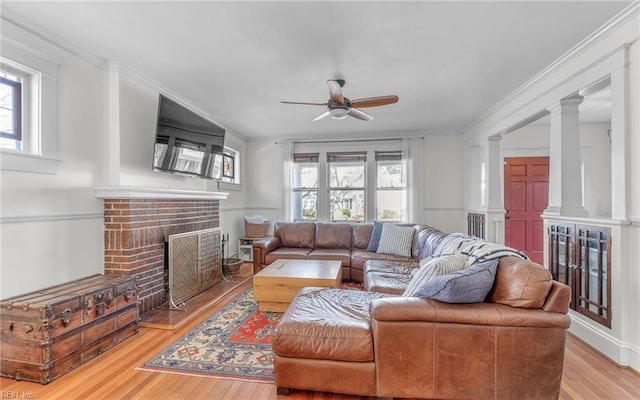 living area featuring wood finished floors, a brick fireplace, ceiling fan, and crown molding