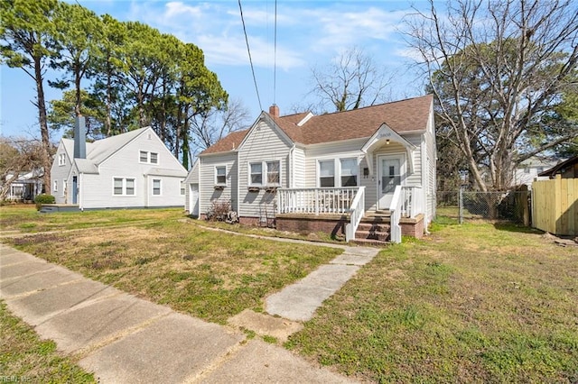 bungalow-style home featuring a gate, fence, a shingled roof, a chimney, and a front lawn