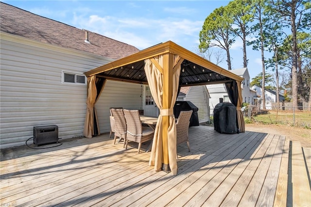 wooden terrace featuring a gazebo, outdoor dining space, grilling area, and fence