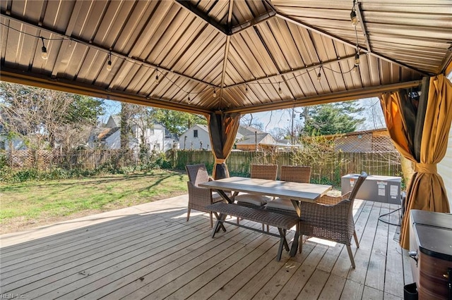 wooden terrace featuring a gazebo, a lawn, outdoor dining area, and a fenced backyard