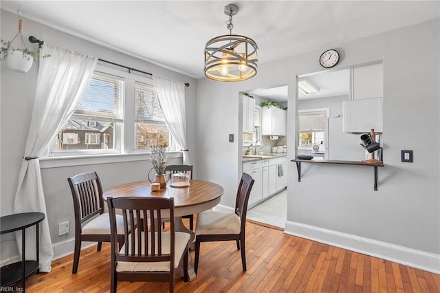 dining room featuring baseboards, a notable chandelier, and light wood finished floors