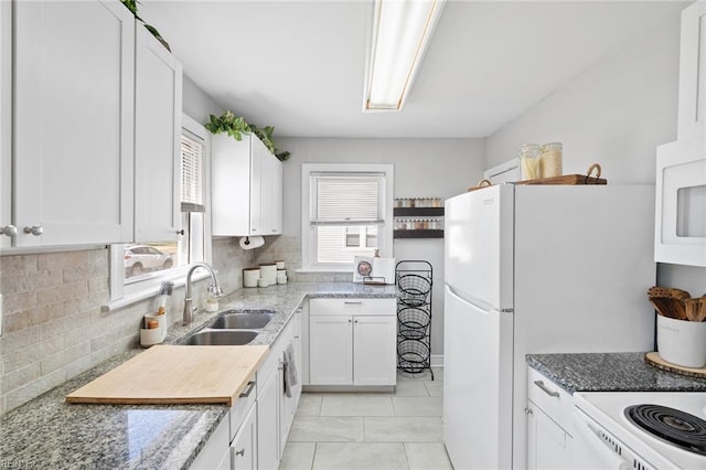 kitchen with a sink, light stone counters, backsplash, white cabinets, and white microwave