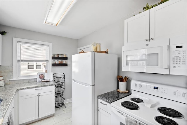 kitchen with light tile patterned flooring, white cabinets, white appliances, and light stone countertops