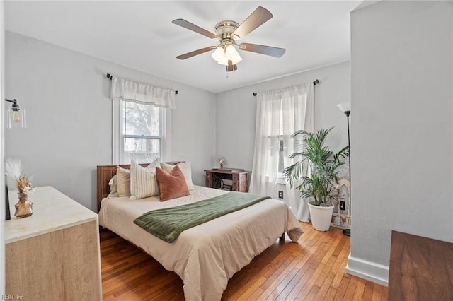 bedroom featuring baseboards, light wood-style flooring, and a ceiling fan