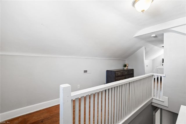 hall with vaulted ceiling, wood finished floors, an upstairs landing, and baseboards