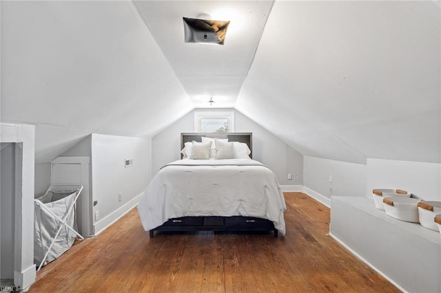 bedroom featuring baseboards, vaulted ceiling, and hardwood / wood-style flooring