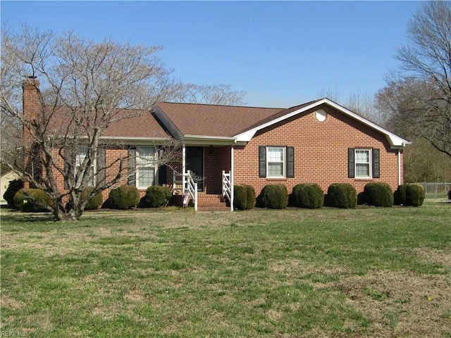 single story home with brick siding, a chimney, and a front yard