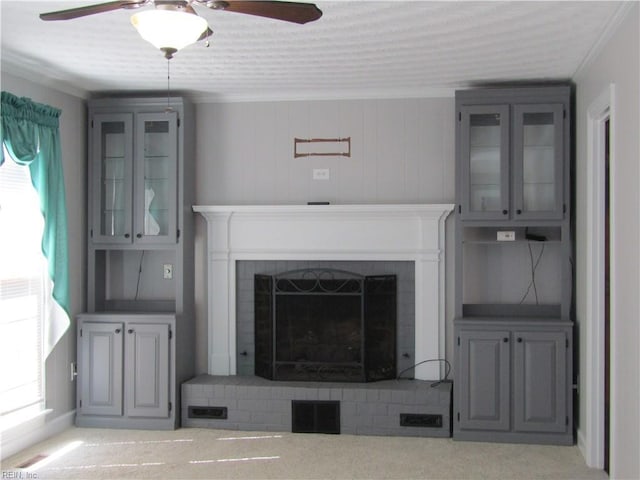 unfurnished living room featuring a brick fireplace, a ceiling fan, and ornamental molding