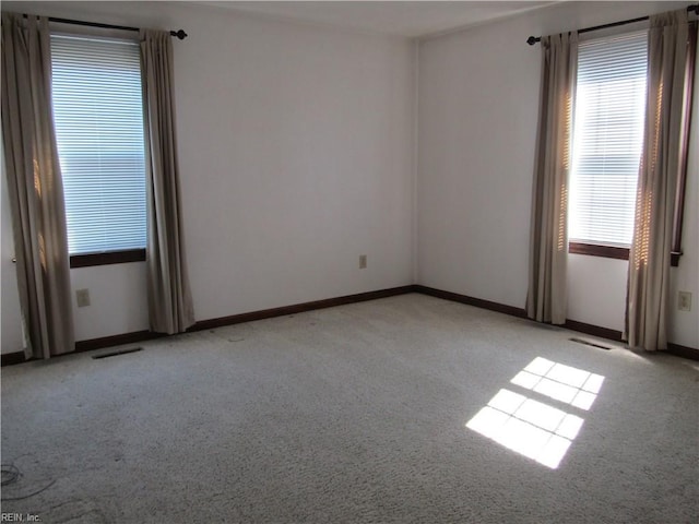 unfurnished room with visible vents, baseboards, and light colored carpet