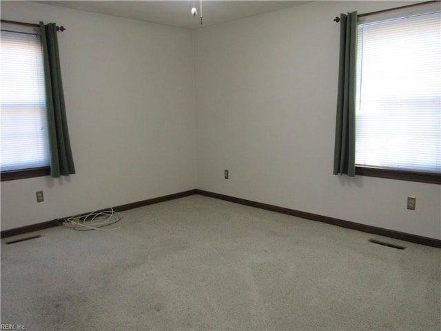 spare room with visible vents, light colored carpet, and baseboards