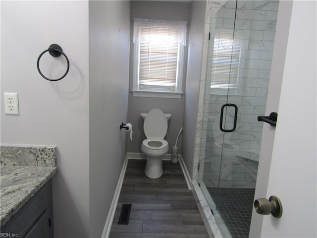 bathroom with vanity, wood finished floors, baseboards, a shower stall, and toilet