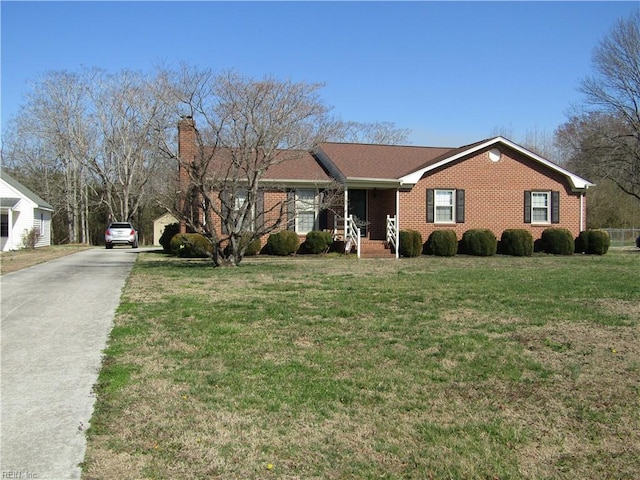 ranch-style home with a front yard, brick siding, driveway, and a chimney