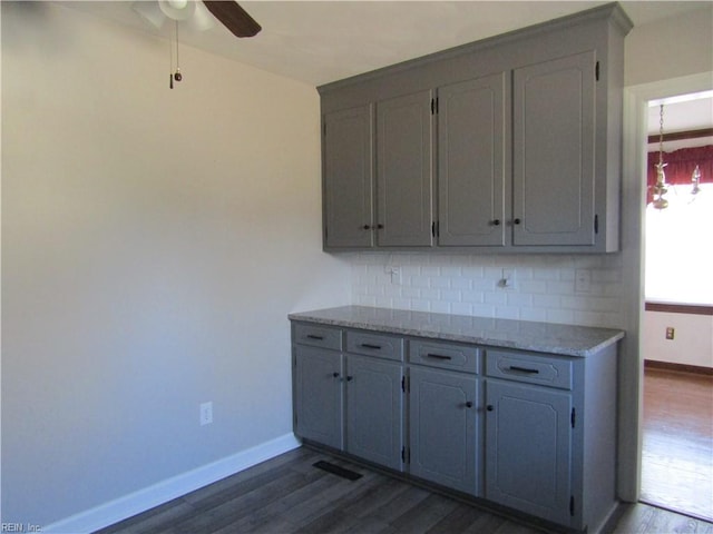 kitchen with decorative backsplash, baseboards, dark wood-style flooring, and a ceiling fan