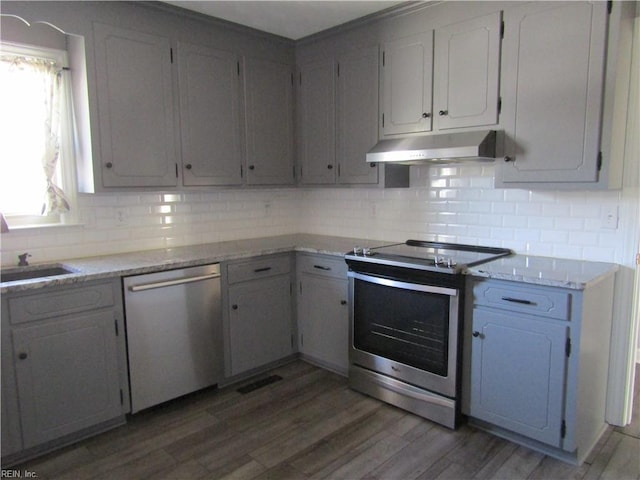 kitchen featuring visible vents, light wood-style flooring, under cabinet range hood, appliances with stainless steel finishes, and decorative backsplash