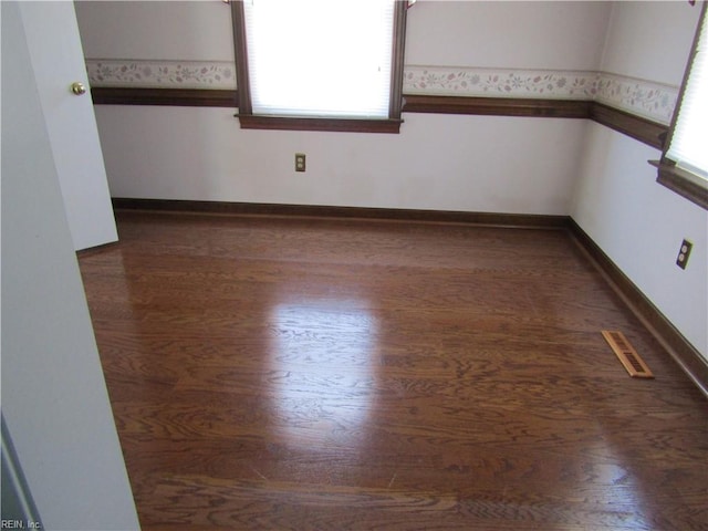 unfurnished room featuring visible vents, baseboards, and wood finished floors