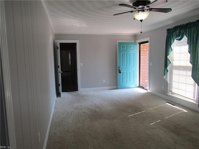 carpeted empty room with ceiling fan, baseboards, and ornamental molding