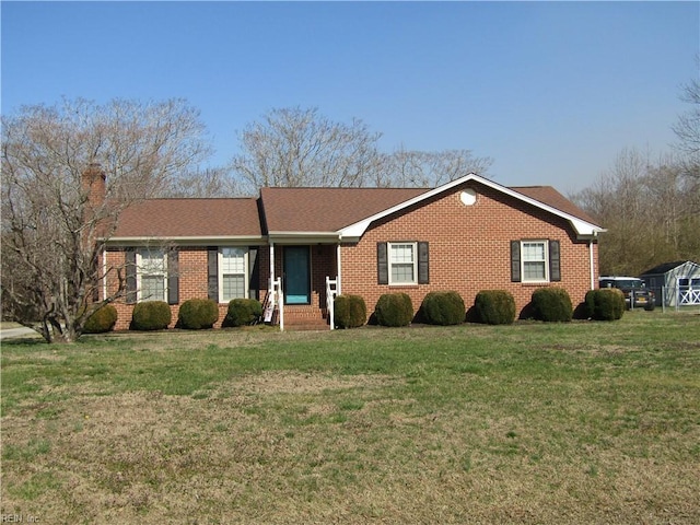 ranch-style home with brick siding, a chimney, and a front yard