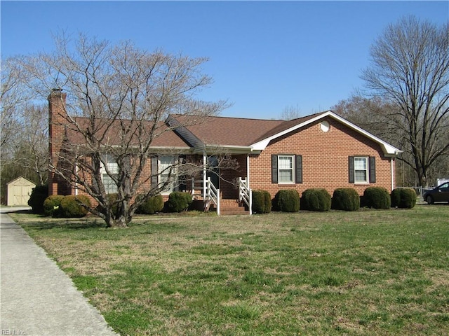 single story home featuring a front yard, brick siding, and a chimney