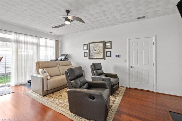 cinema room featuring ceiling fan, visible vents, a textured ceiling, and wood finished floors