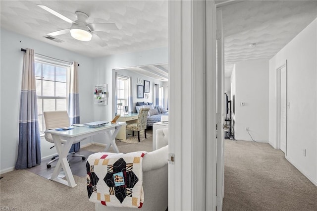 carpeted home office featuring visible vents, baseboards, and ceiling fan