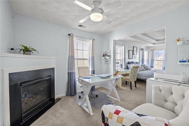 office space with visible vents, baseboards, carpet, ceiling fan, and a fireplace with flush hearth